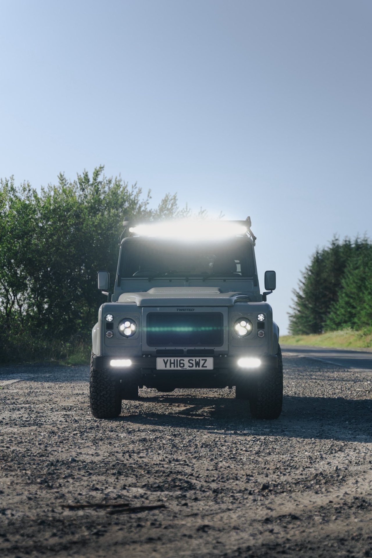 Twisted Land Rover Defender at sunrise with full beams on